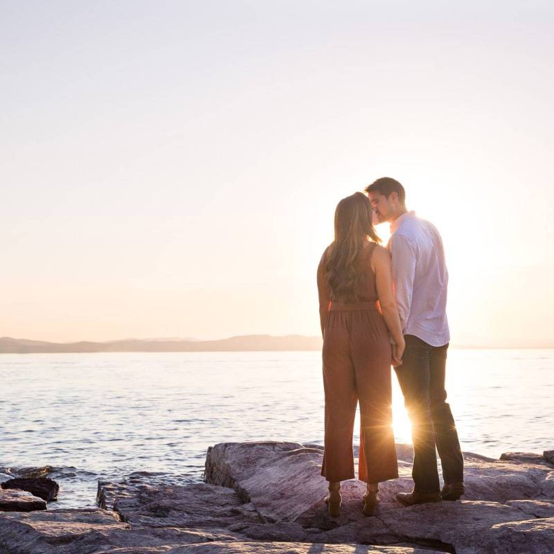 Couple kissing in engagement photo on Lake Champlain, Vermont at sunset
