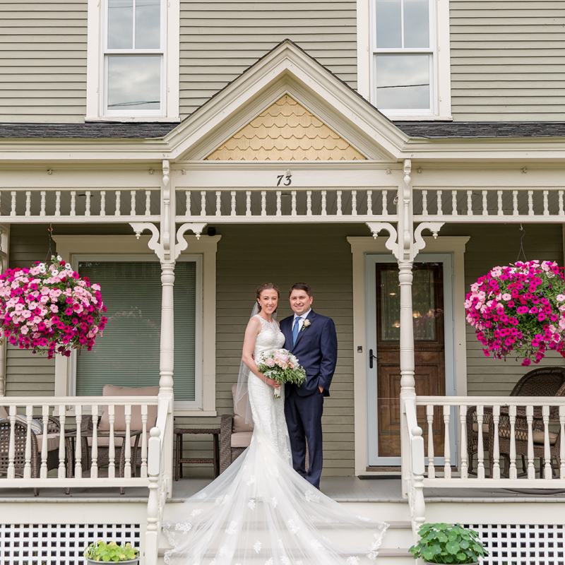 Bride and groom standing on stairwell outside house smiling on their Vermont wedding day