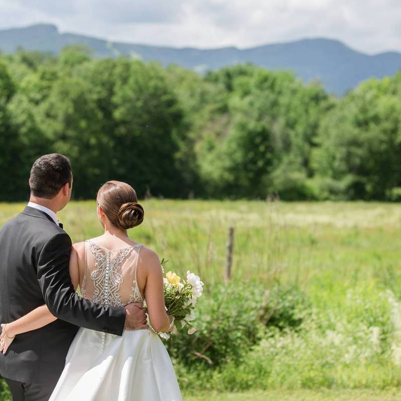 White couple in elegant wedding attire gazing at the mountains of Vermont