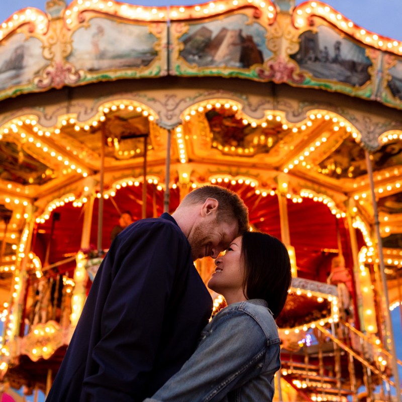 Couple kissing in front of carousel at carnival engagement shoot in Vermont