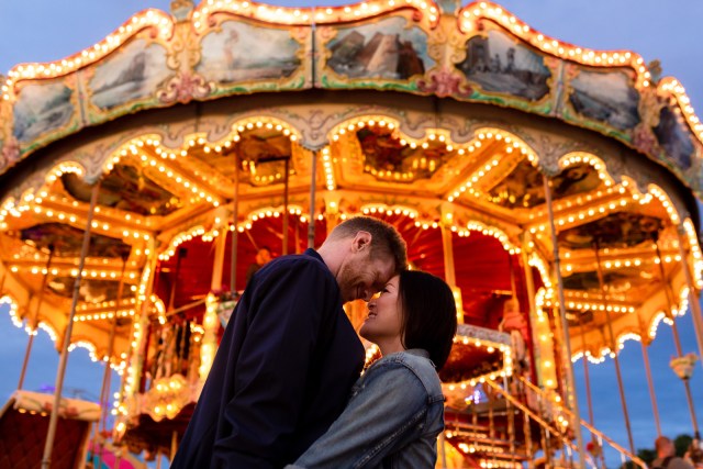 Couple kissing in front of carousel at carnival engagement shoot in Vermont
