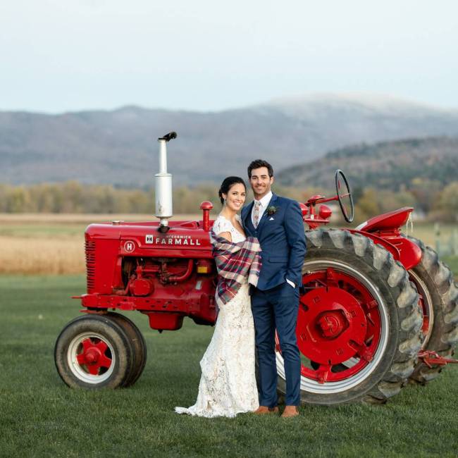 Photo of bride and groom in front of tractor at fall wedding at the Barn at Boyden Farm in Vermont