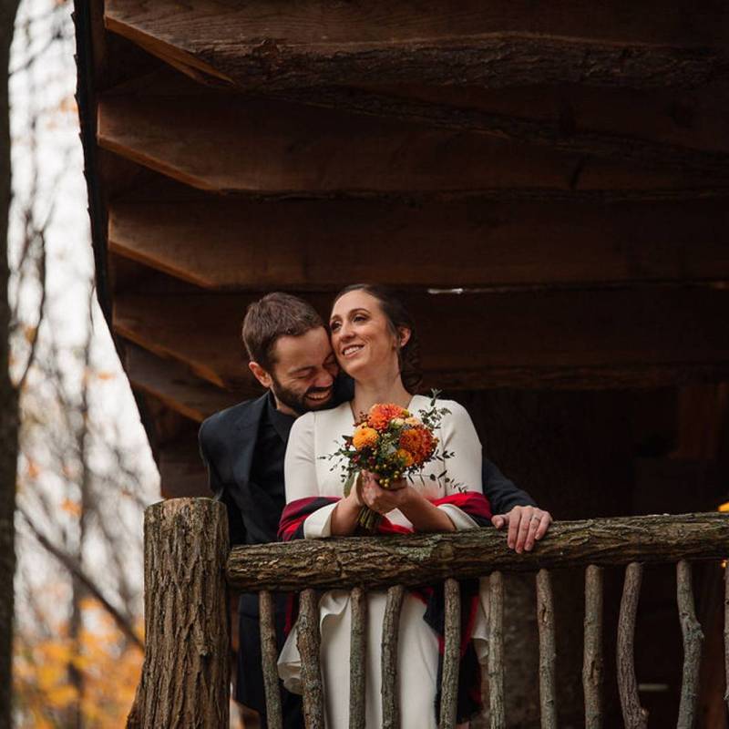 Couple looking out from the deck of a treehouse during fall Vermont elopement