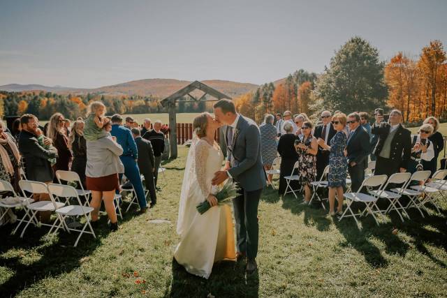 Bride and groom kissing at the end of their outdoor ceremony aisle during Vermont wedding at the Inn at Grace Farm