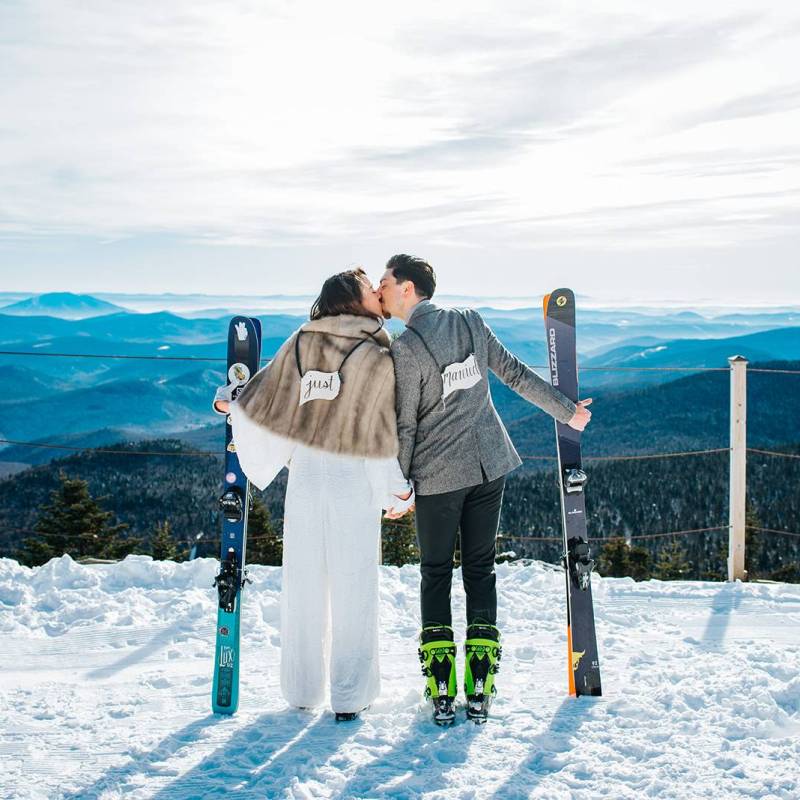 Couple holding skis after elopement ceremony on the summit of Killington Mountain in Vermont