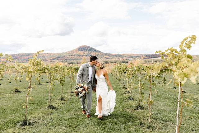 White bride and groom kissing in vineyard in Milton, Vermont