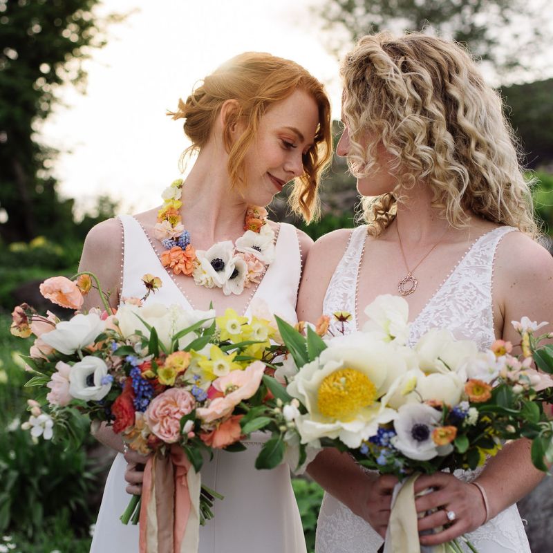 Two brides nuzzling while holding large bouquets during a spring elopement styled shoot in Vermont