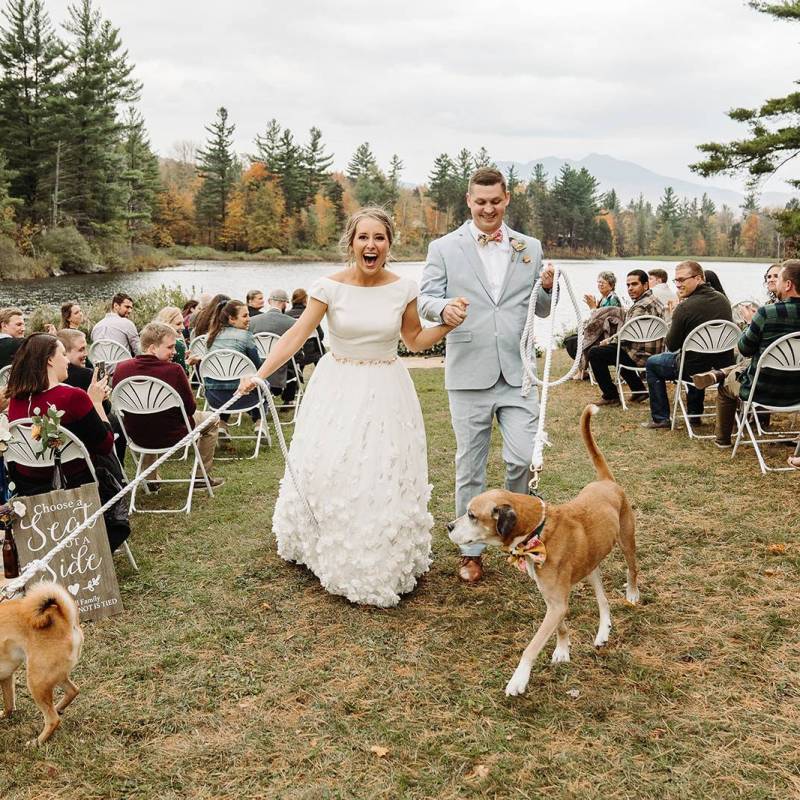 A white couple walks their two dogs down the aisle after getting married at Sterling Ridge Resort, VT