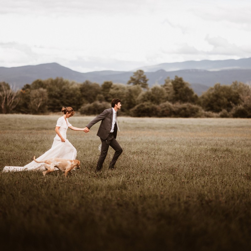 Bride and groom walking through field during Vermont wedding