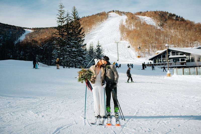 Couple kissing at bottom of ski slope after their Vermont winter elopement